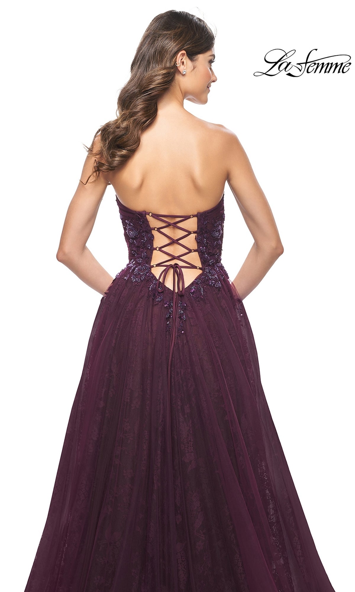 Woman in a deep purple La Femme Strapless Long Prom Ball Gown 31954 with sweetheart neckline, lace-up back, and floral details, shown from behind.